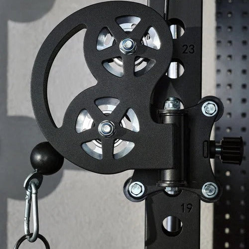 Close-up of a mechanical pulley system on a gray wall.
