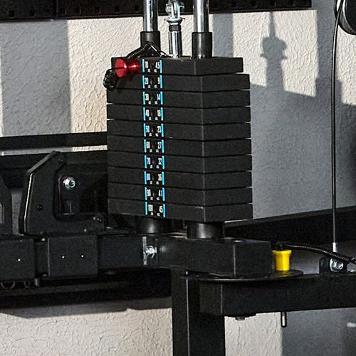 Stack of black weight plates on a weightlifting machine with a blurred background