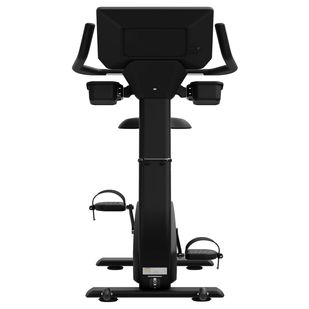 A black upright exercise bike with a large digital display screen on the back, armrests, and foot pedals, shown from a front-facing perspective against a solid white background.