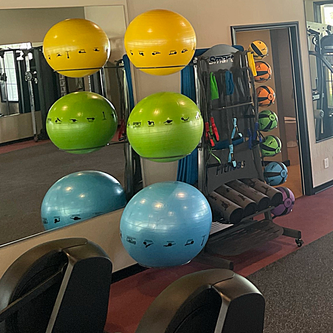 Colorful exercise balls on a rack in a gym setting