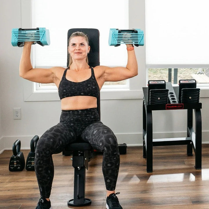 Woman exercising with blue dumbbells in a home gym setting