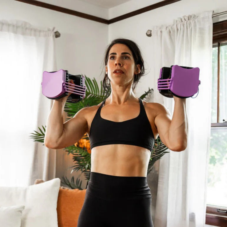 Woman exercising with purple dumbbells in a home setting