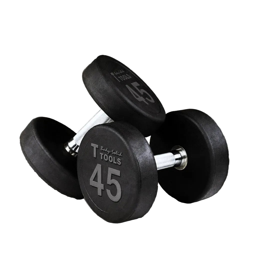 Two black rubber-coated dumbbells with silver metal handles, each marked 45 lbs, displayed on a concrete floor against a gray wall.