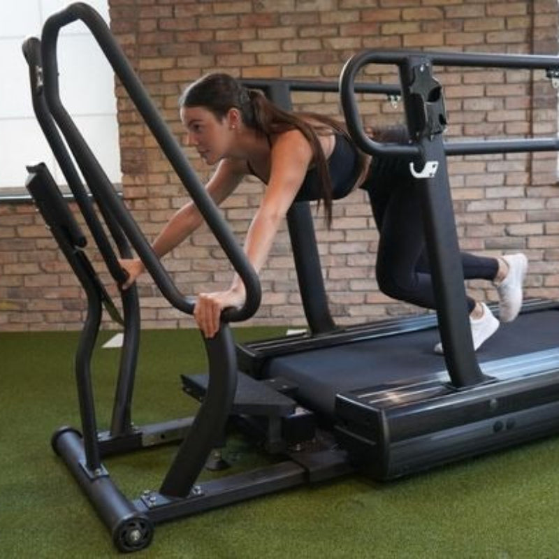 Woman using a treadmill with an inclined platform in a gym setting.