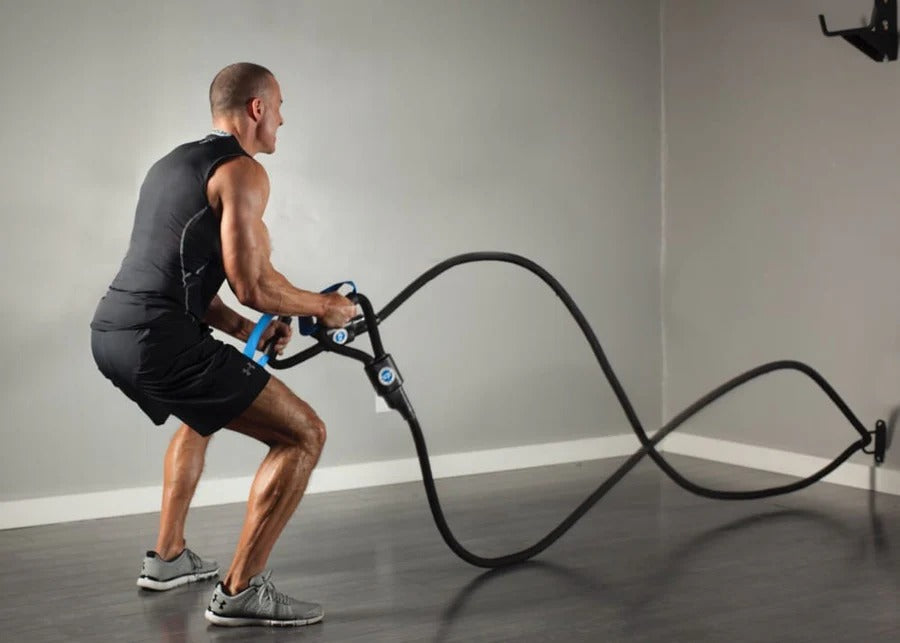 Man exercising with battle ropes in a gym setting