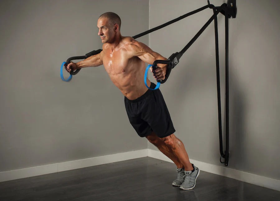 Man exercising with suspension straps in a home gym setting