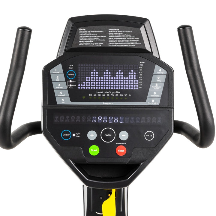 Close-up of an exercise bike console with black handlebars, a digital display screen, and control buttons including blue, green, gray, and red on a white background.