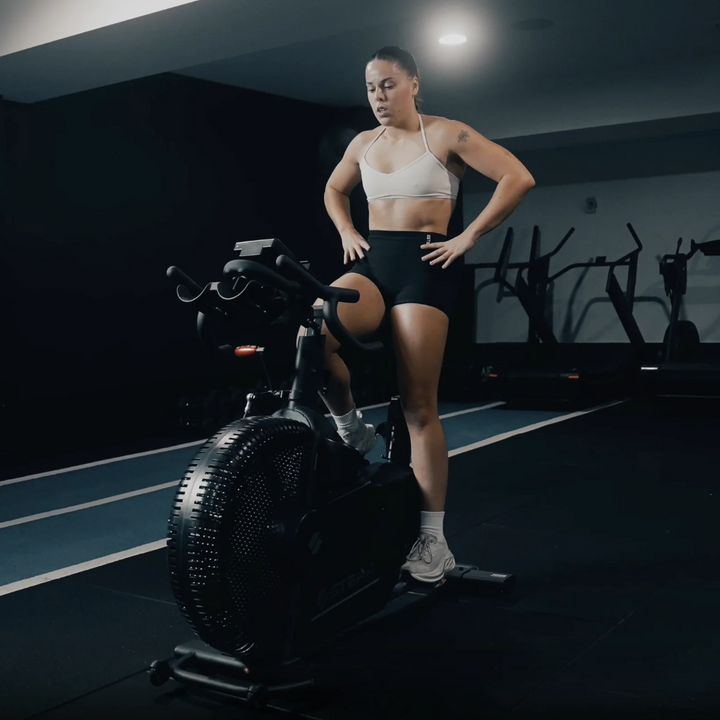 Woman on a stationary bike in a dark indoor setting
