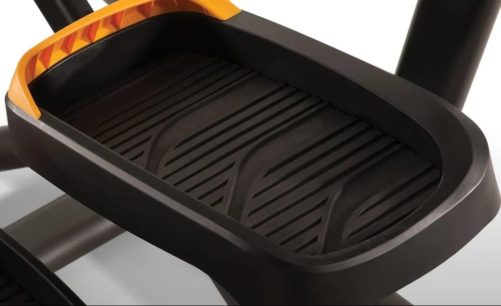 Close-up of a black elliptical trainer step with a ribbed tread surface and orange accent trim.