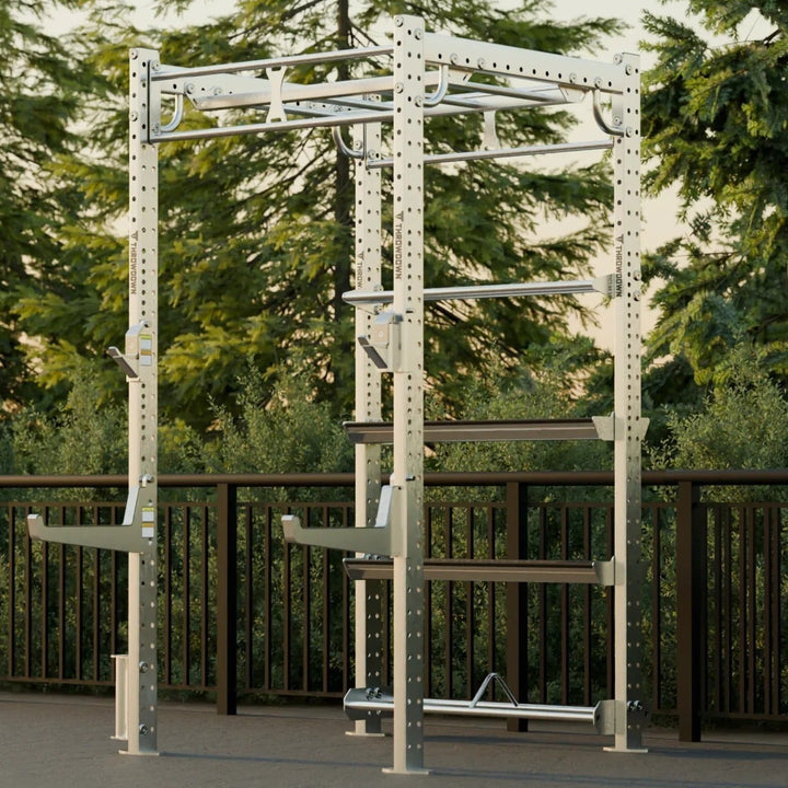 Outdoor fitness equipment in a park setting with trees and a wooden fence.
