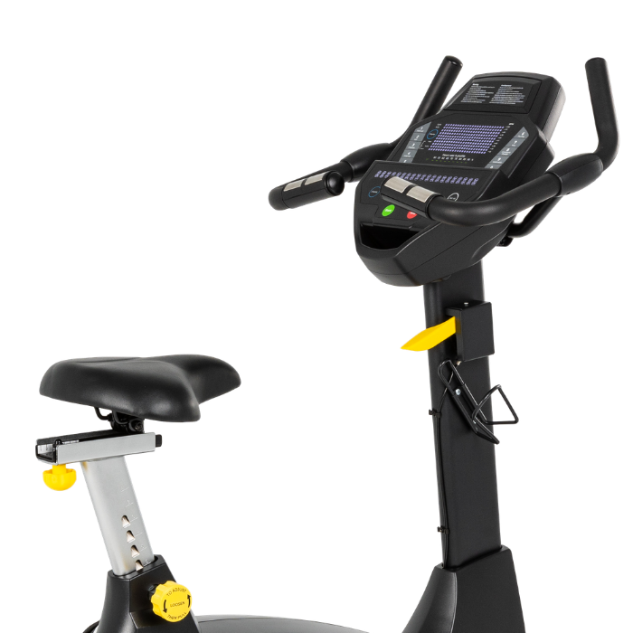 A close-up of a stationary exercise bike showing the black seat, silver adjustment column with yellow knobs, and the black console handlebar unit with a digital display screen, isolated on a white background.