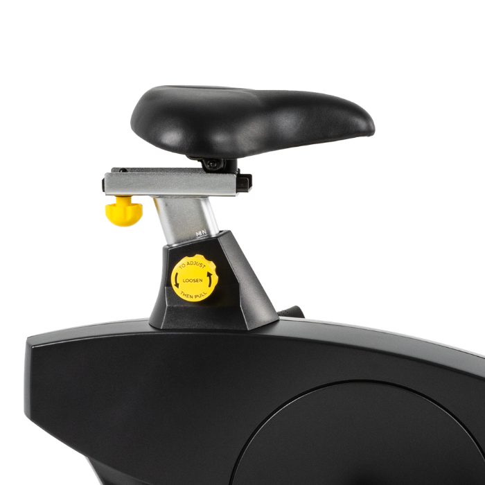 Close-up of a black indoor exercise bike showing the seat, adjustment mechanism, and part of the frame against a white background.