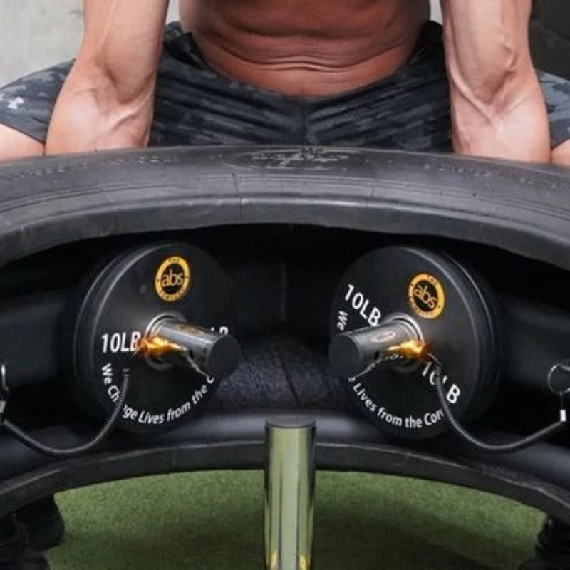 Person using a tire flip device with weights attached, on a concrete surface.