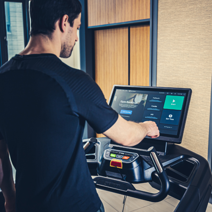 Man using a treadmill with a digital display in a modern indoor setting