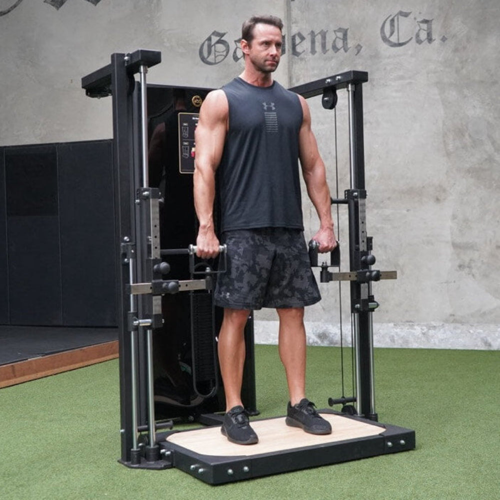 Man using a cable machine in a gym setting with a concrete wall and &