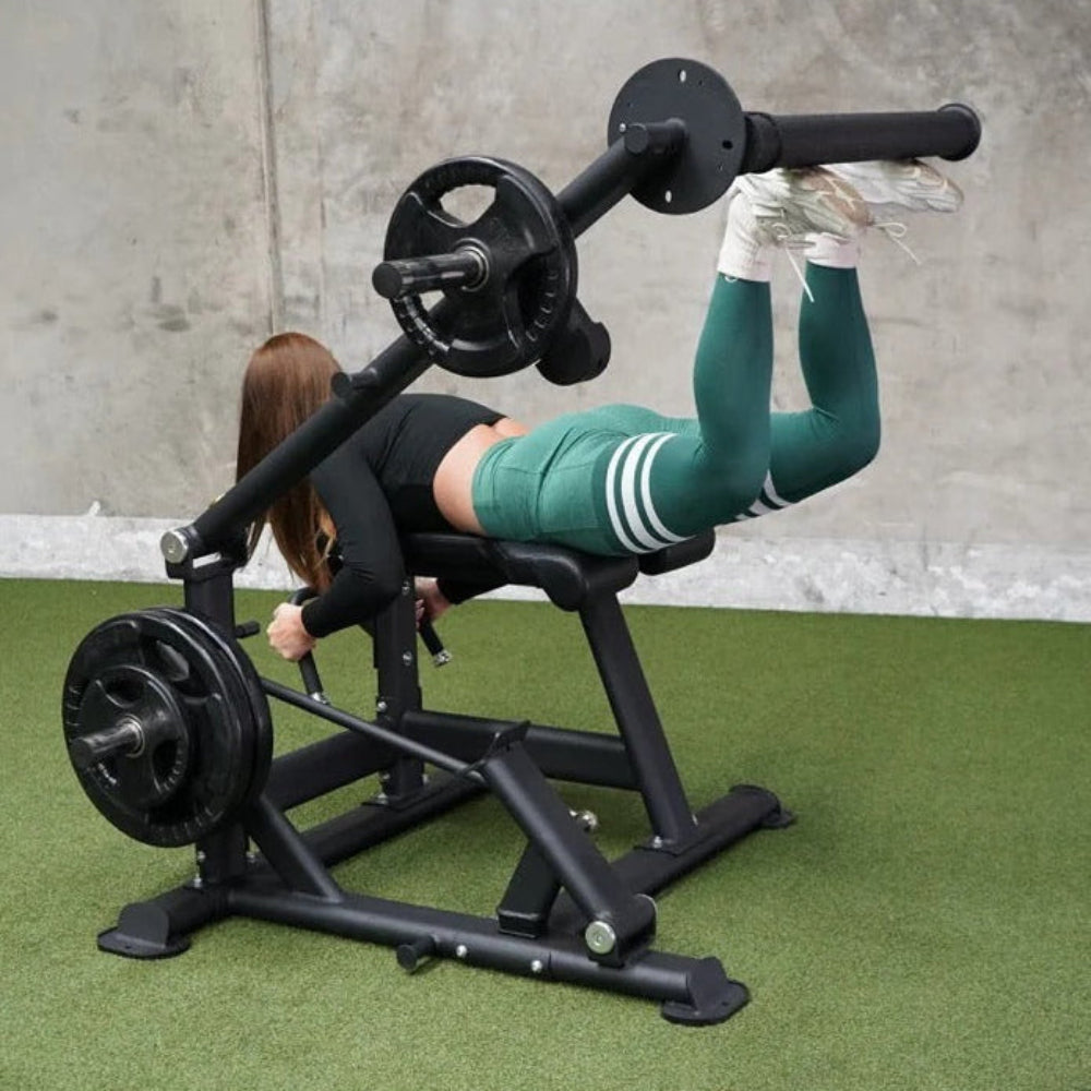 Person using a weight machine on a green floor with a concrete wall background